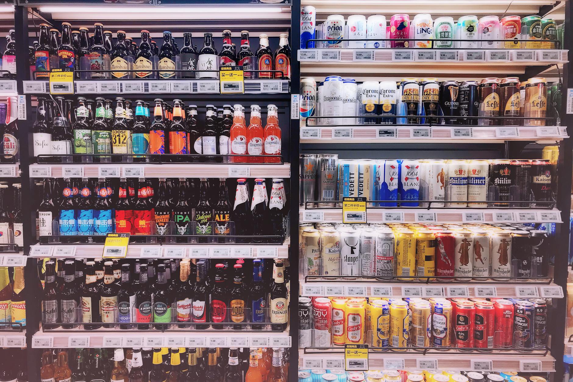 Drinks display in a convenience store fridge – rows of beer and soda cans.